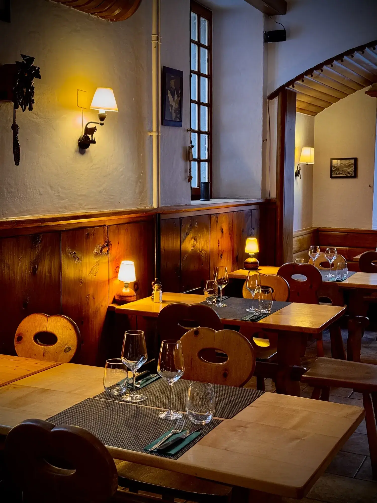Ambiance du soir au Carnotzet, tables de bois et lumière tamisée — Grand Hôtel & Kurhaus Arolla